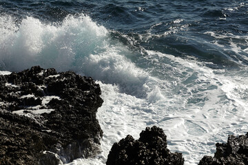 Foam wave on a rock. Splashing waves on a rock in the summer sun