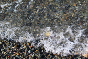 Waves left bubbles, pebbles, and summer memories on a beach 
