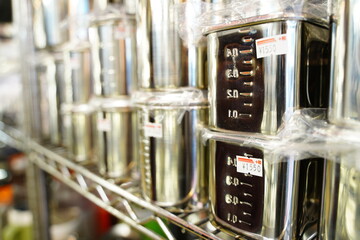 Japanese text on price seal is "tax". Metal measure cups on shelf at Kappabashi,Tokyo,Japan.