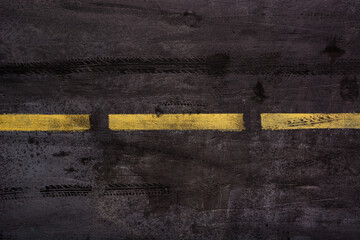 Imitation of asphalt road surface with traces of car tires and stripes of yellow markings in grunge style