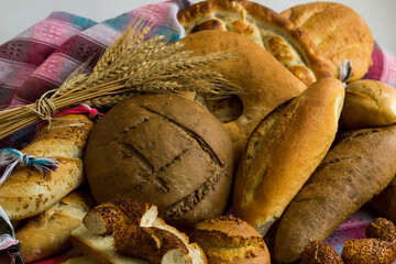 Rye breads and white flour breads on the fabric table cloth with a bunch of wheat head.Close up taken of group breads.