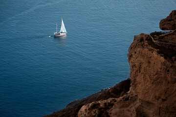 Yacht sailing across Aegean sea pictured from the top of the cliff