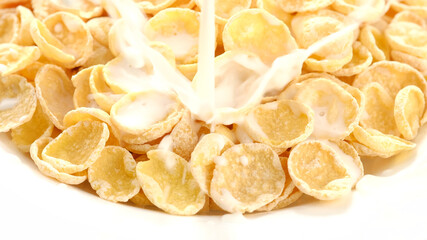 corn flakes pouring milk in white plate closeup. top view. healthy food breakfast