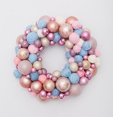 wreath of Christmas balls and clews on white wall. New year decoration in tender pink and blue colors