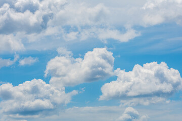 various shape fluffy cummulus clouds accumulating on blue summer sky