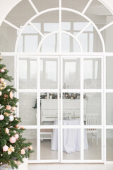 Arch door in a room decorated for celebrating Christmas. Luxury interior in white colors. 