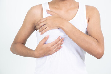 Woman hand checking lumps on her breast for signs of breast cancer on gray background. Healthcare concept.