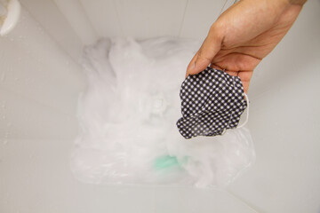 Cleaning a fabric face mask by use a washing machine and powder laundry detergent to kill coronavirus, covid 19 and reuse surgical mask after outdoor activity.