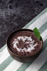Black Glutinous Rice Porridge or Bubur Pulut Hitam in Malay with coconut milk on dark background on top napkin