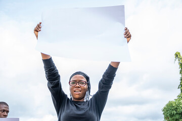 a black woman at a protest holding up a sign with free copy space