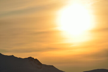 huge golden sunset over snowy mountain peak background