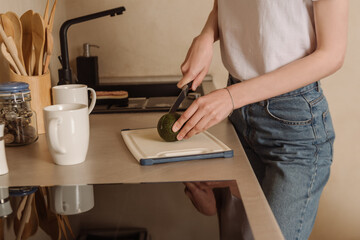 Fototapeta na wymiar cropped view of woman cutting tasty avocado near cups