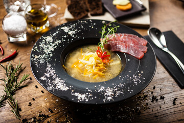 Clear Fish soup served with slices of tuna in a bowl. Delicious healthy Italian traditional food closeup served for lunch on a table in modern gourmet cuisine restaurant