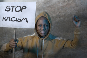 young outraged and hipster African American woman holding protest banner demanding stop racism and...
