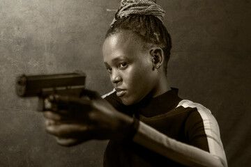 Hollywood movie style portrait of young attractive and confident black African American woman holding gun as special federal agent or mobster pointing the handgun
