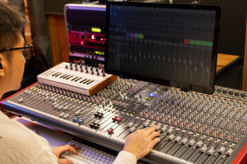 male sound engineer, producer, composer mixing music on audio mixer in recording studio