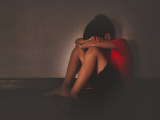 Asian lonely child boy are sitting in the dark with sadness and unhappy.