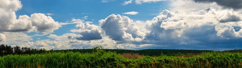 Fototapeta na wymiar A huge panorama of huge clouds over a beautiful landscape