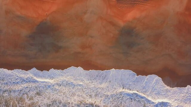Flying over a sandy beach. Waves break on a sandy beach on the Atlantic coast, aerial View. Nazare, Portugal.