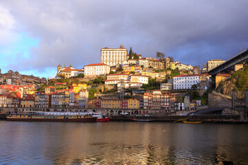 Morning in Porto Portugal: Dark clouds in the sky above Douro river and Ribeira district, featuring sunlit Episcopal palace on the top of the hill.