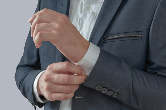 Man buttoning on the sleeves isolated on gray background
