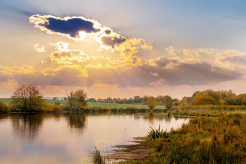 Autumn landscape with picturesque sky over the river during sunset, reflection of the sky in the river