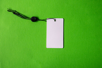 White blank price label tag on green background.