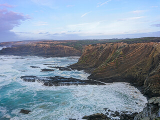Obraz premium Strong waves hit rocky cliffs