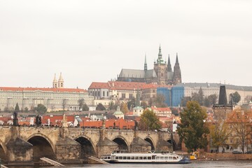 Charles bridge (Karluv Most) and the Prague Castle (Prazsky hrad) seen from the Vltava river with a tourist boat passing by. The castle is the main touristic landmark of the city.