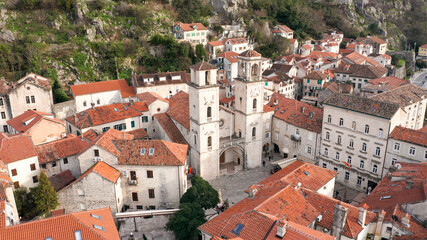 Fototapeta na wymiar Kotor medieval old town and major tourist destination in Montenegro, featuring The Cathedral of Saint Tryphon from 12th century. Aerial view of vintage stone houses with red roofs, on a sunny day.