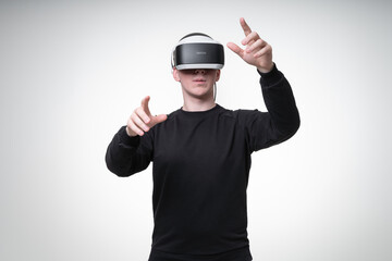 European man with dark hair wears VR goggles which covers almost all his face, he gesticulates and touches air around