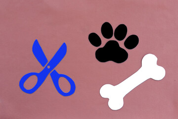 Pet paw print, scissors, bone like dog food on pink background. Haircut of Pets.