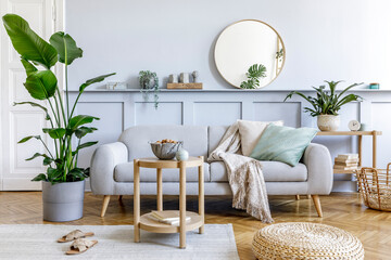 Stylish living room interior with design grey sofa, coffe table, pouf, basket, shelf, mirror,...