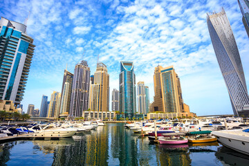 Fototapeta na wymiar Marina for small boats and yachts in Dubai UAE, surrounded by tall skyscrapers. Luxury vacation tourist destination and real estate investment and development opportunity. Skyline of a modern city.