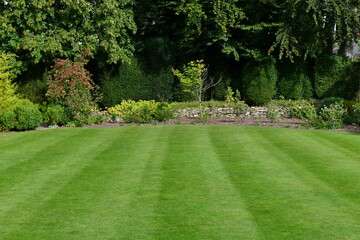 Landscape View of a Beautiful English Style Garden with a Fresh Mowed Lush Grass Lawn, Colourful Flower Bed and Leafy Green Foliage
