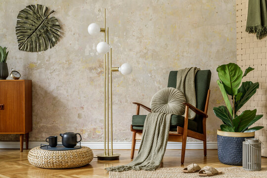 Modern retro composition of living room interior with design armchair, pouf, tea pot on the tray, plant, plaid, carpet, decoration and elegant presonal accessories in wabi sabi concept.