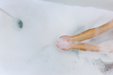 the child plays in a bathtub filled with white foam, palms hold foam for bathing