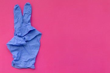 A blue medical glove on a pink background points out the 