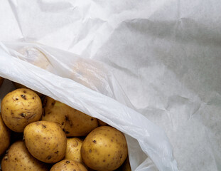 A pile of unwashed potatoes lies in a white bag
