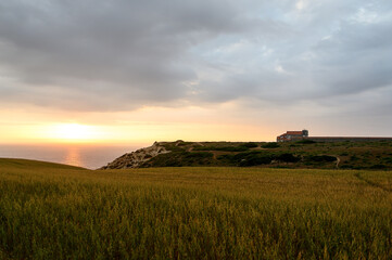 Fototapeta premium Old church in Portugal on a hill by the ocean at sunset.