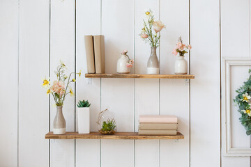 shelf with flowers and books on white wall