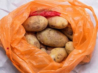 A pile of unwashed potatoes lies in a bright bag