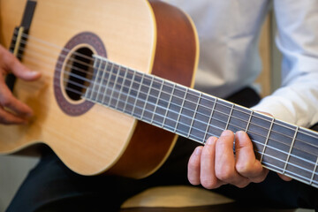 Fototapeta na wymiar Classical guitar - Guitarist playing acoustic guitar in studio - selective focus close-up of the fingerboard and hand 