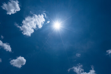Naklejka na ściany i meble Bright blue sky with clouds and sun ray