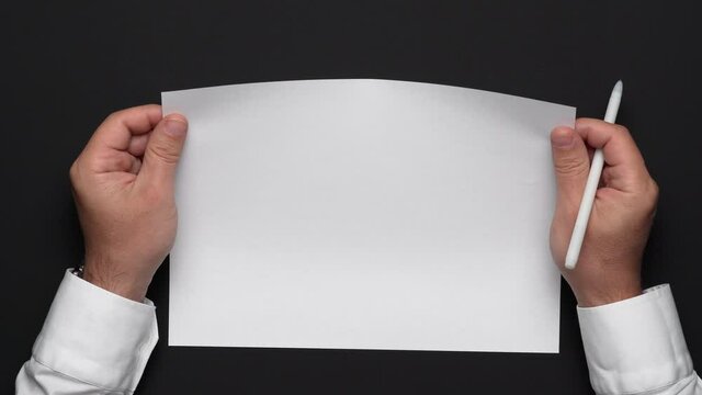top view of a blank sheet of paper and a businessman's hands on a black table, white shirt and wrist watch