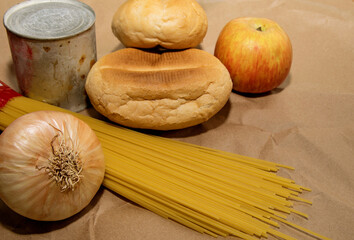 Obraz na płótnie Canvas apple, spaghetti, onions, bread and canned goods lie on a paper bag
