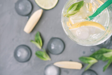 Ingredients for making mojito on grey background. lime, lemon, mint leaves and high glass with ice cubes. summer non-alcoholic cocktail. top view