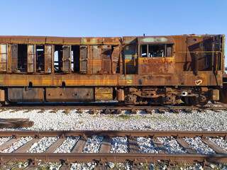 Demolished rusty locomotive in a railway junkyard. Dilapidated vintage diesel engine covered with rust.