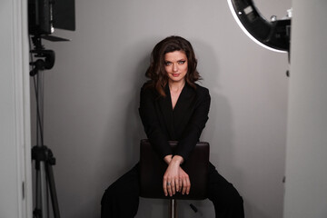 Young beautiful sexy model in black suit posing in photo studio. Studio photo light