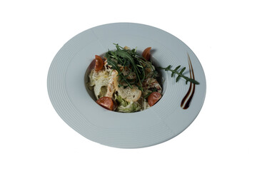 Caesar salad with chicken, lettuce, croutons, arugula tomatoes in a white plate on a white background. Restaurant serving dishes.